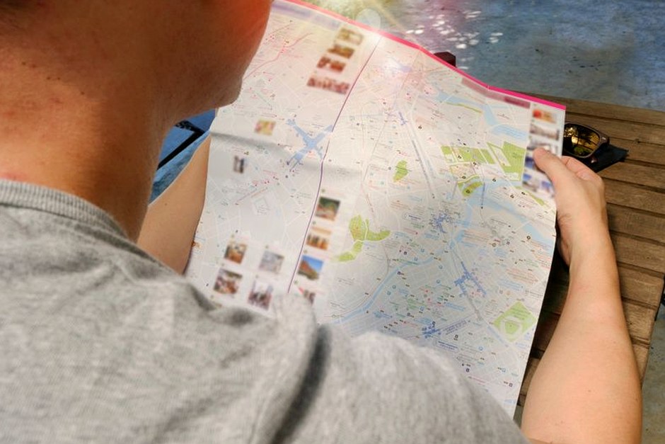 A traveler studies a paper map, representing careful context and preparation.