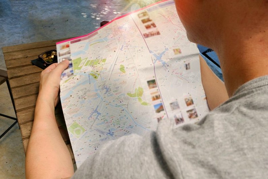 A traveler reading a paper map outdoors.